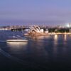 A stunning view of the Sydney Opera House and harbor illuminated at twilight, showcasing city life and architecture.